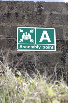 an assembly point sign on a block wall in Ireland