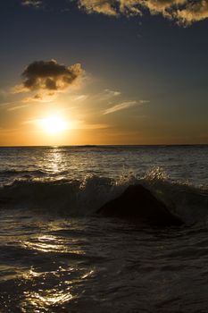 Wave crashing on a rock at the beach during sunset