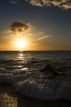 Wave crashing on a rock at the beach during sunset