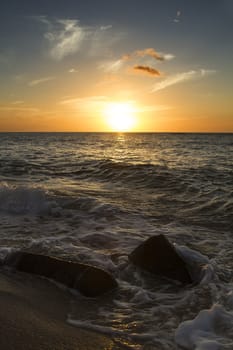 small waves rolling over rocks at the beach during sunset