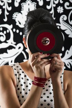 young woman looking through the hole of a small dusty record with a red label