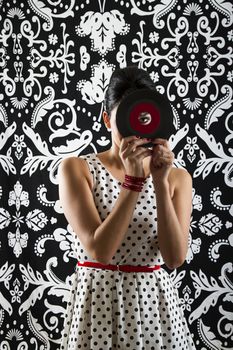 young woman looking through the hole of a small record with a red label