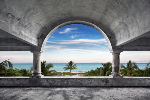 A high dynamic range photo of a view of the ocean from inside an old abandoned mansion.