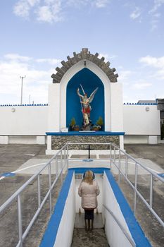 a woman praying at a statue of saint michael slaying the devil with a healing holy well in Lixnaw county Kerry Ireland