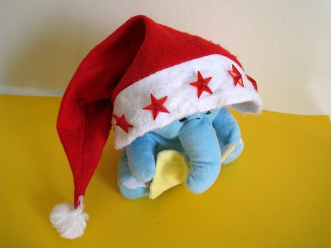 a soft toy of elephant reading book wearing a christmas hat