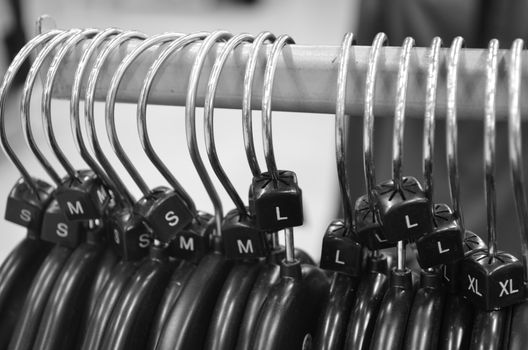 Monochrome of plastic hangers on rail with sizes