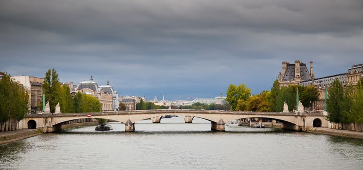 Panorama of Paris on gloomy sky background - view on Pont du Carrousel. Musee d'Orsay on the left and Louvre on the right.