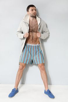 Stylish man in shorts on a gray background