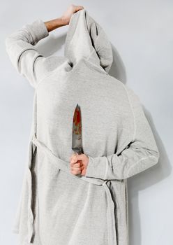 Man with a bloody knife on a gray background