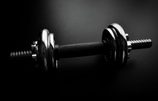 Close-up of an chrome dumbbell on dark background