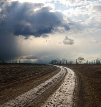 dramatic sky over field with dirty road