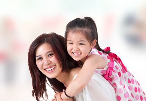 Asian family at home. Mother and child piggyback ride at indoor room.