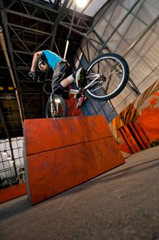 Cyclist standing on orange box in park on front wheel