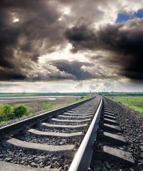 view to railroad goes to horizon under cloudy sky with sun