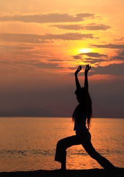 A woman exercising/stretching at sunset by the beach