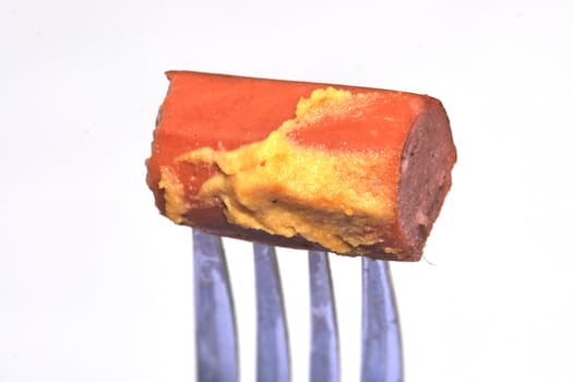 hot dog sausage on fork with mustard