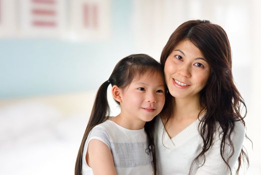 Portrait of adorable young girl and mother at home. Happy Asian family.