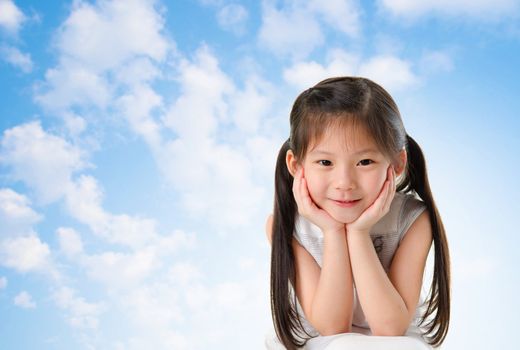 Young Asian girl with smile on her face sitting outdoor in summer day, blue sky background