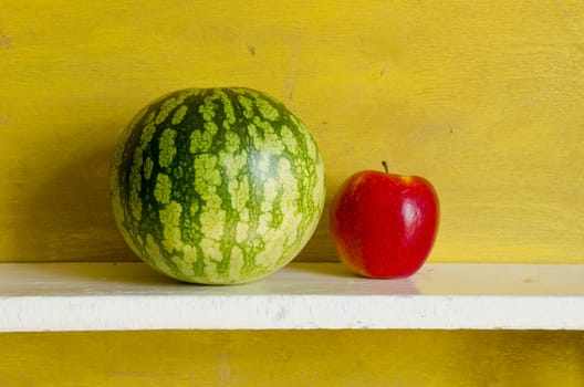 Watermelon and red apple on shelf. Healthy natural fruit food.