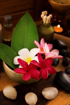 Spa still life setting with aromatic candles, frangipani flower, cold and hot stones.