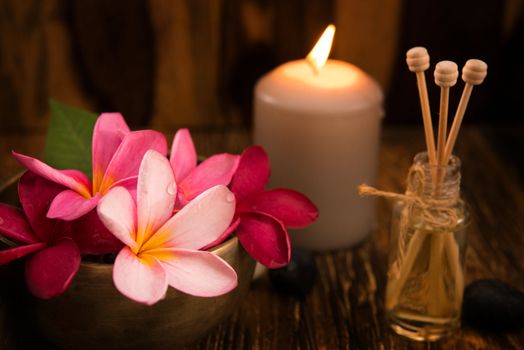 Wellness and spa concept with candles, frangipani flower, sandalwood and rattan sticks on massage table.