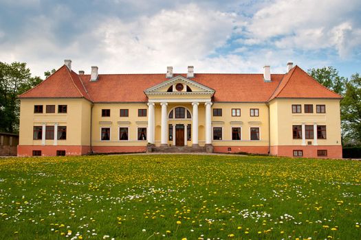 Durbe manor house near Tukums, Latvia with dandelion field in front