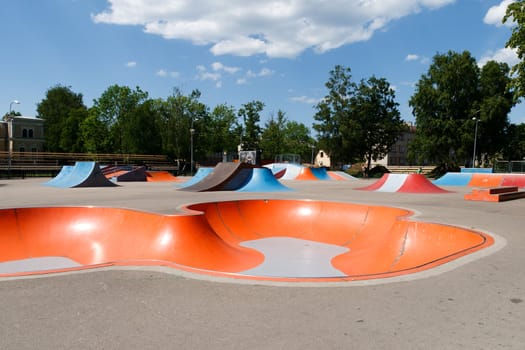 Empty skatepark with colorful ramps in sunny day