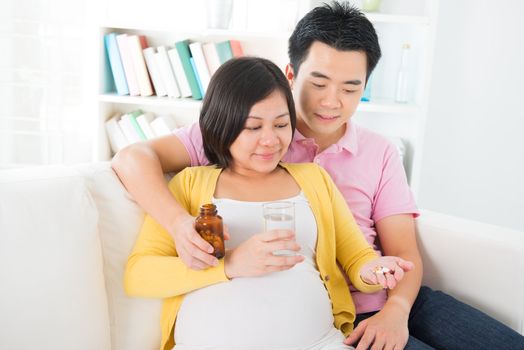 Asian pregnant woman having medicine at home. Asian pregnant couple living lifestyle.