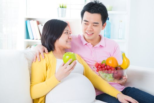 Pregnant woman eating fruits at home. Pregnancy couple healthcare concept.