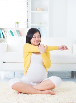 Maternity health concept. Asian pregnant woman yoga at home.