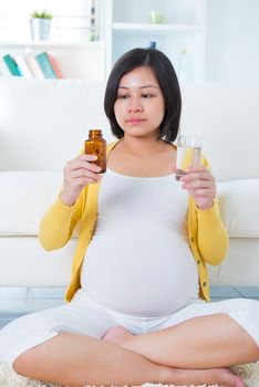 Pregnant woman taking supplements at home. 