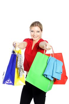 Happy young blonde woman shopping for clothing holding out an array of brightly coloured carrier bags overflowing with garments isolated on white