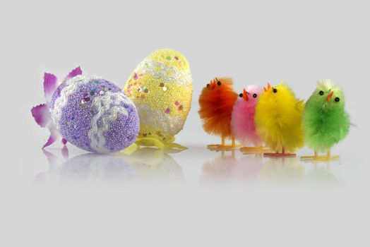 Four colour Easter chick and two eggs decorated in a light grey background