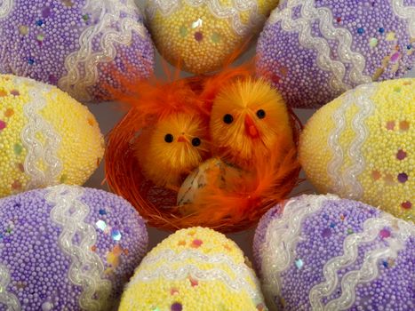 Two red Easter chicks in the nest surrounded by decorated eggs