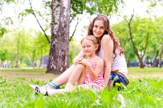 mother and daughter sitting together on the grass, and spend time with family