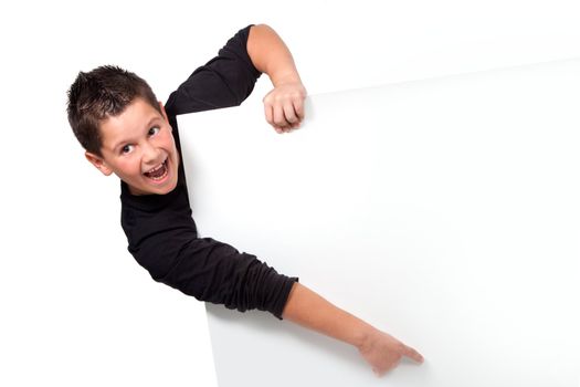 Smiling teen boy pointing finger on blank board with copyspace