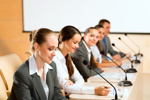 businessmen communicate at the conference, sitting at the table, on the table microphones and documents