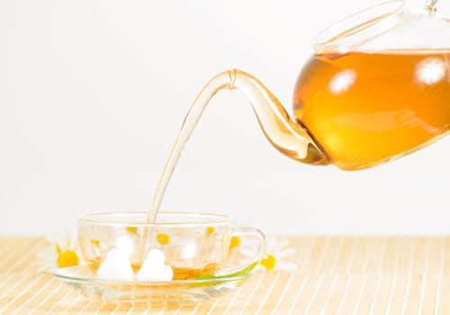 A teacup and a teapot with herbal chamomile tea