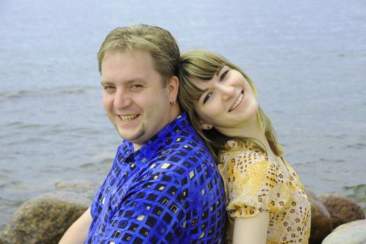 Young couple in love sitting together outdoors in the sea beach