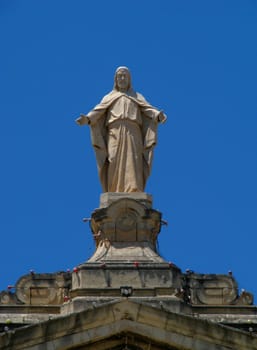 A statue of Our Lord Jesus high up on a church's rooftop in Marsa, Malta.