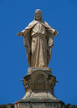 A statue of Our Lord Jesus high up on a church's rooftop in Marsa, Malta.