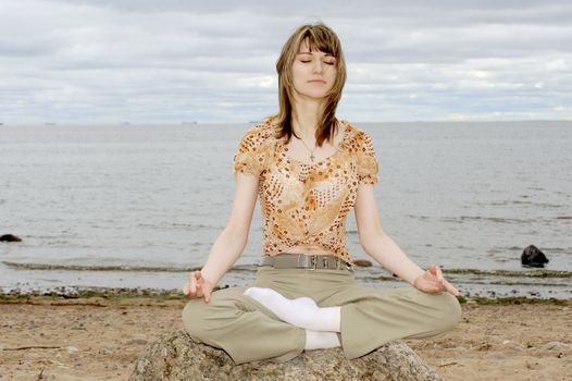 Woman doing joga on the sea beach