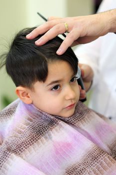 A lovely child in the hairdresser salon cutting his hair