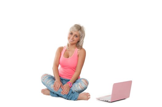 girl in a pink shirt, blue jeans sitting with a laptop