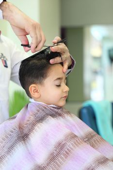 A lovely child in the hairdresser salon cutting his hair