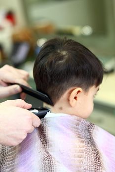 A lovely child in the hairdresser salon cutting his hair