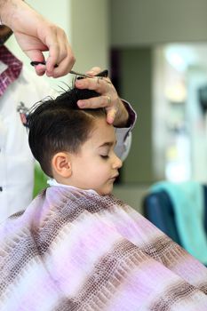 A lovely child in the hairdresser salon cutting his hair