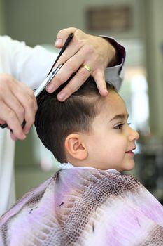 A lovely child in the hairdresser salon cutting his hair