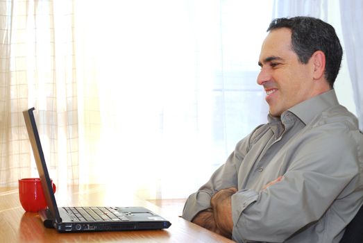 Man sitting at his desk with a laptop looking happy