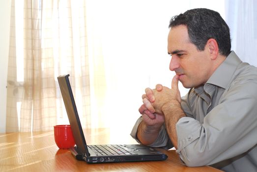 Man sitting at his desk with a laptop looking thoughtful